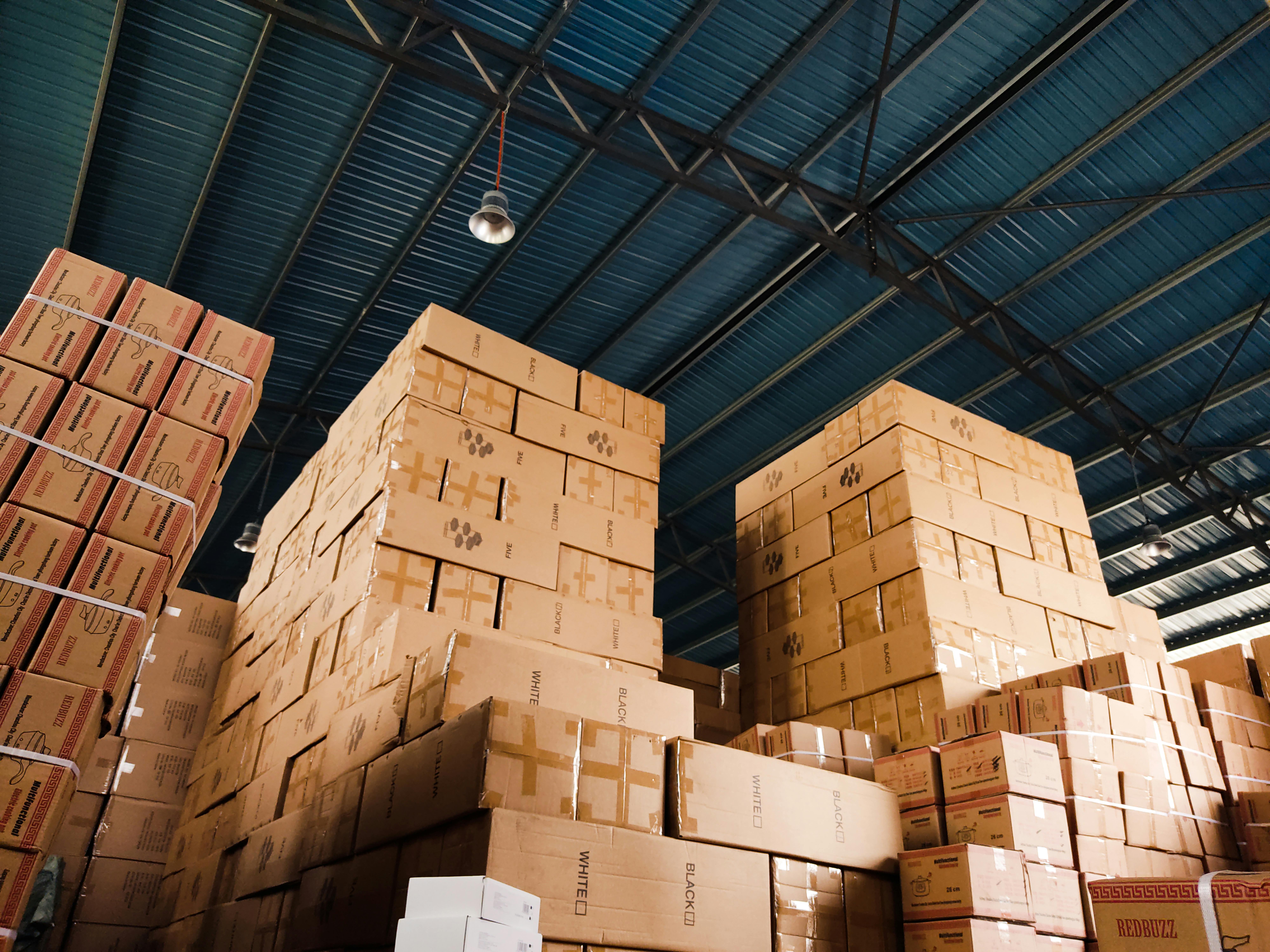 High stacks of cardboard boxes organized in a warehouse with a blue metal ceiling.