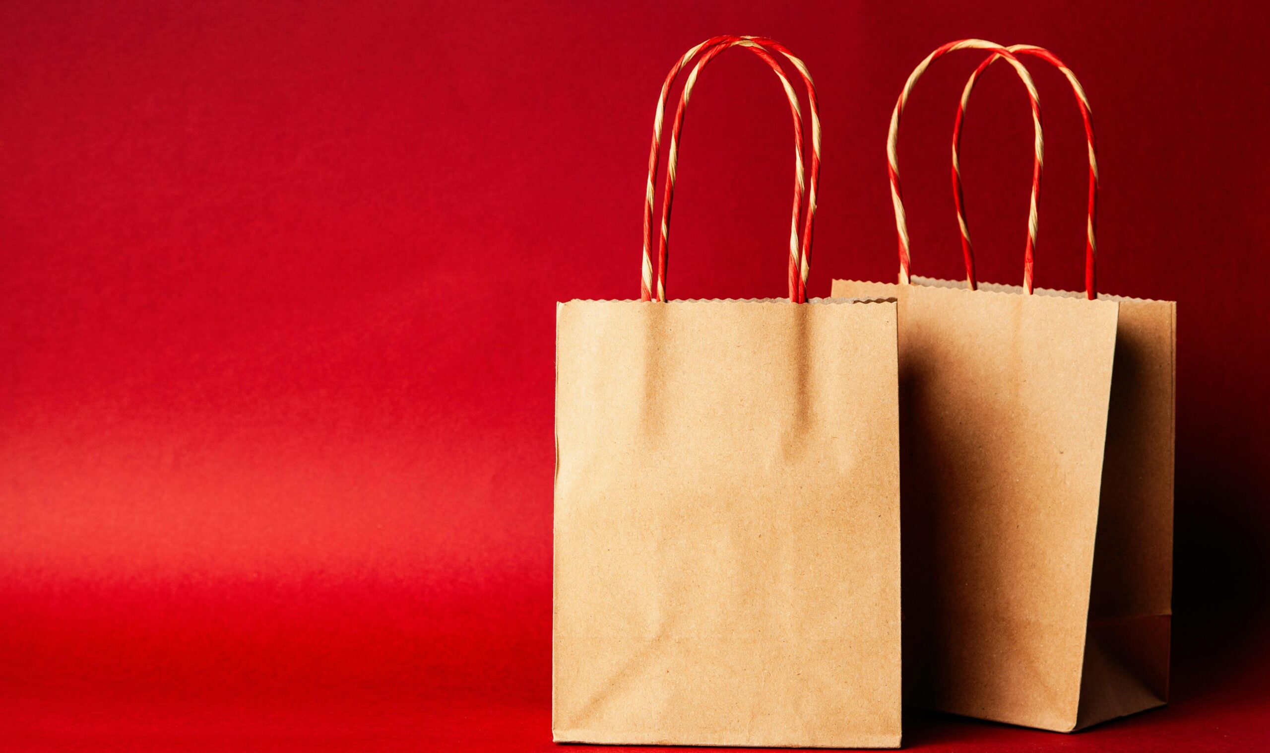 pexels-photo-1666067-1666067-1 Simple brown paper bags with handle on a festive red backdrop, perfect for Christmas.