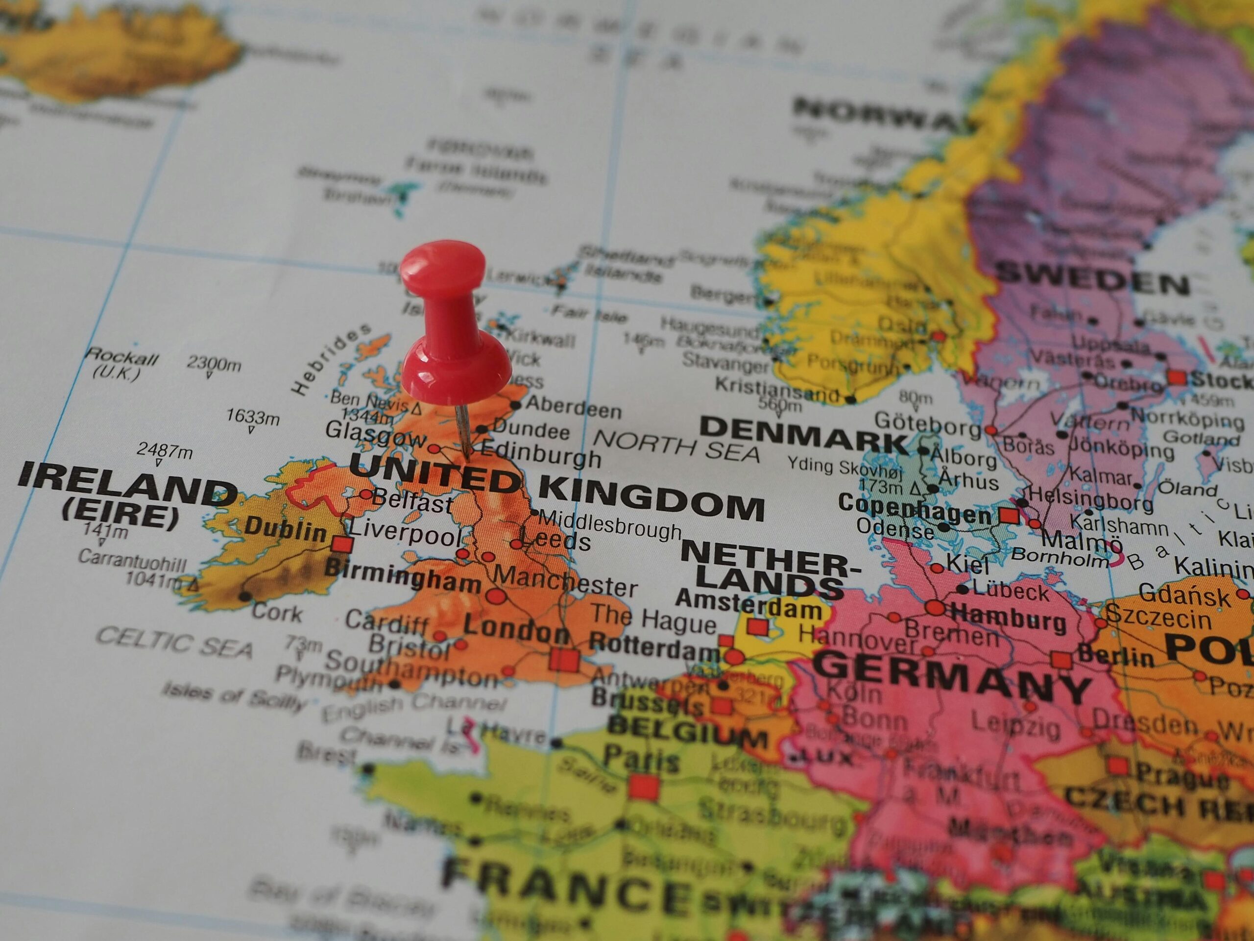 pexels-photo-19963850-19963850 Close-up of a European map highlighting the UK with a red pin, perfect for geography themes.
