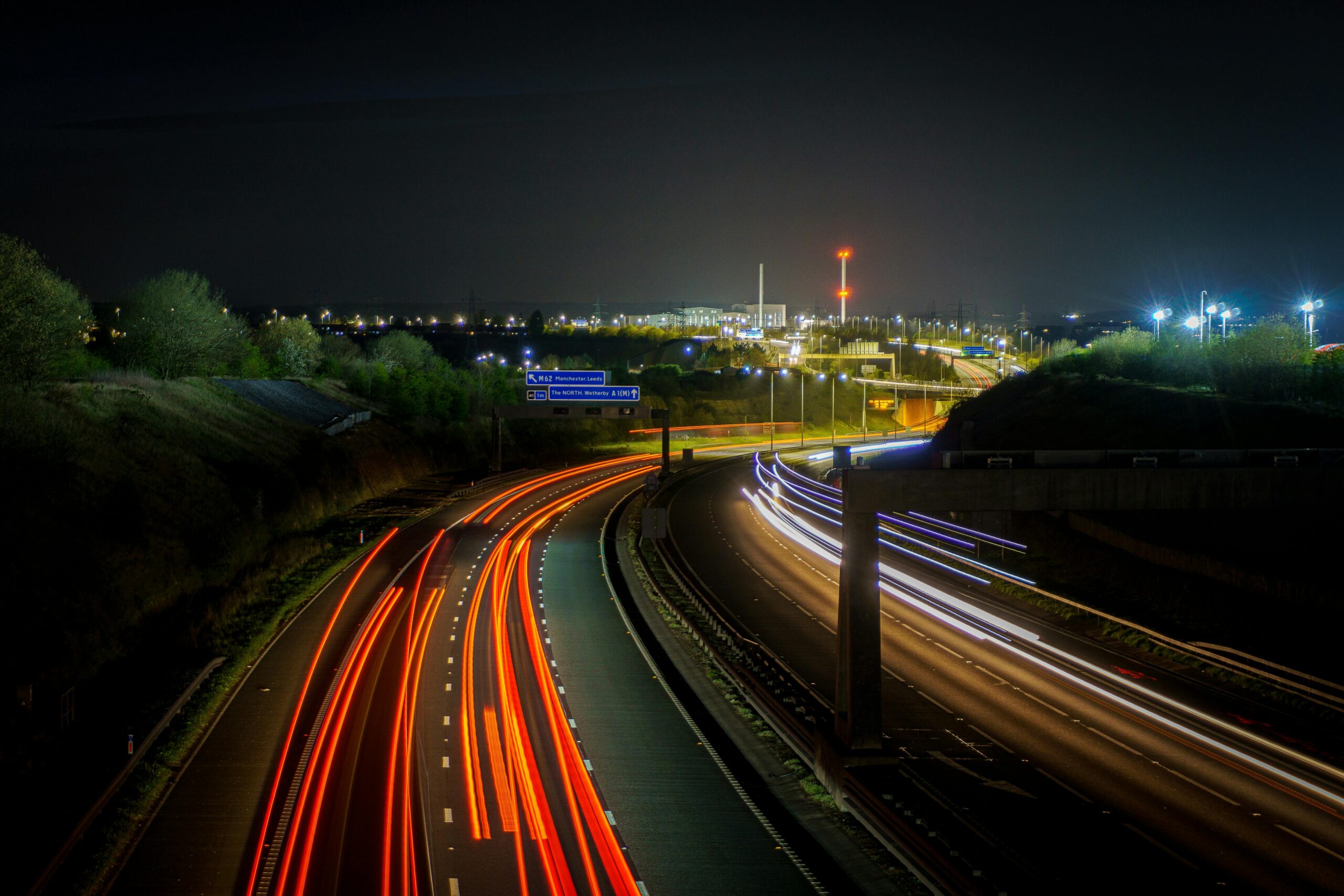 Long exposure shot of a UK highway at night featuring vivid light trails from passing cars.