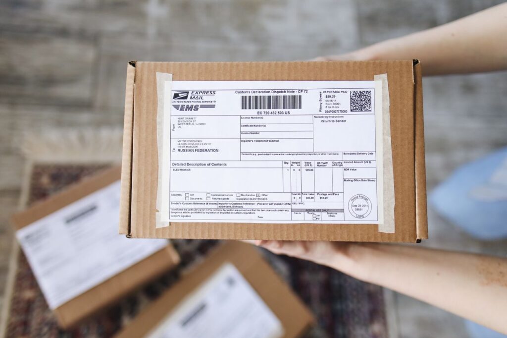 pexels-photo-4440788-4440788 Top view of hands holding an express mail parcel with a customs declaration.