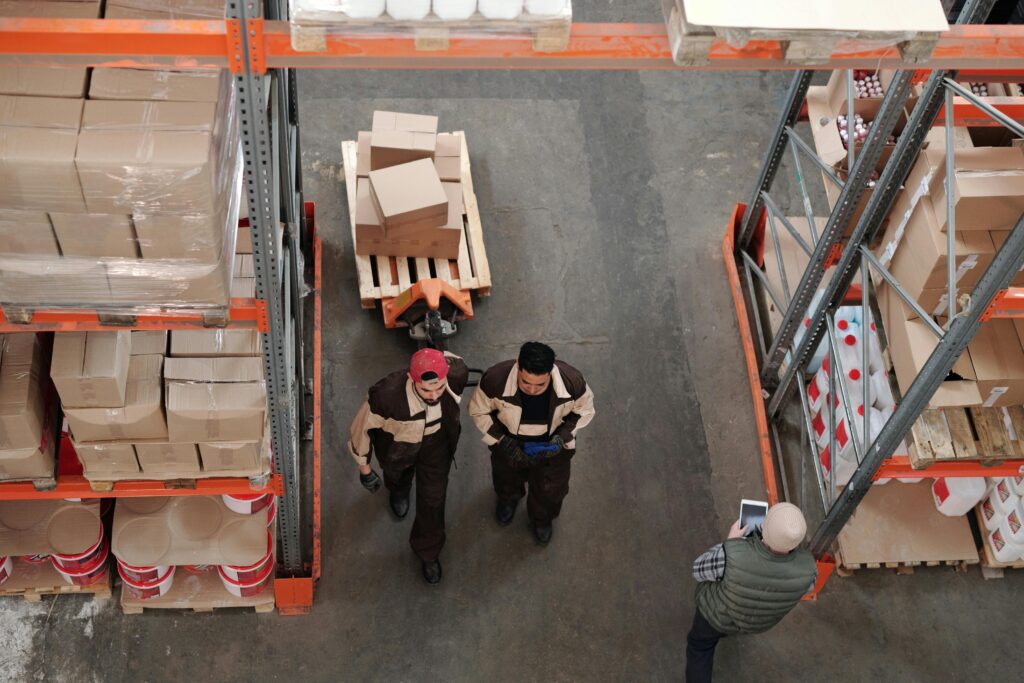 High angle view of courier service workers organizing and preparing shipments with boxes and pallets.