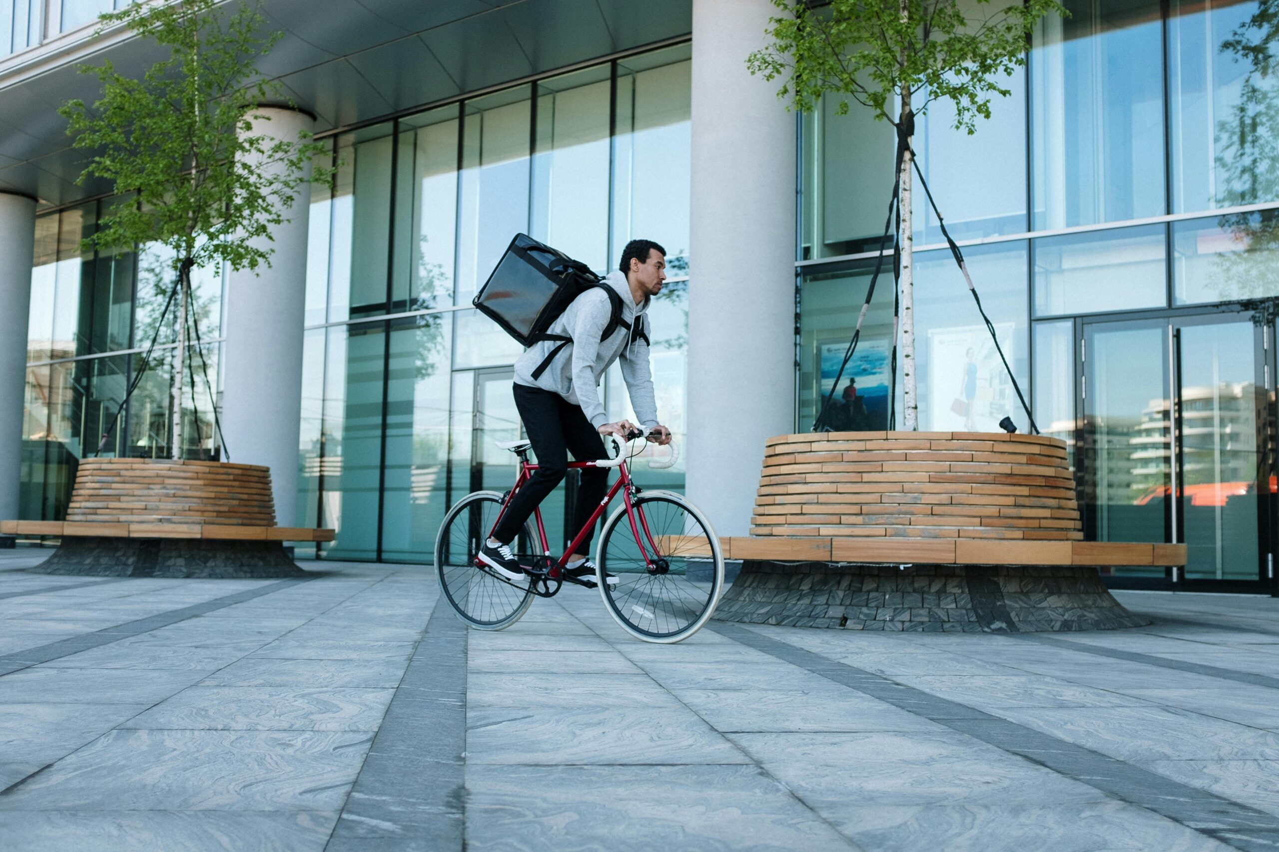 pexels-photo-4604599-4604599 Bicycle courier delivering packages in an urban setting with modern architecture.