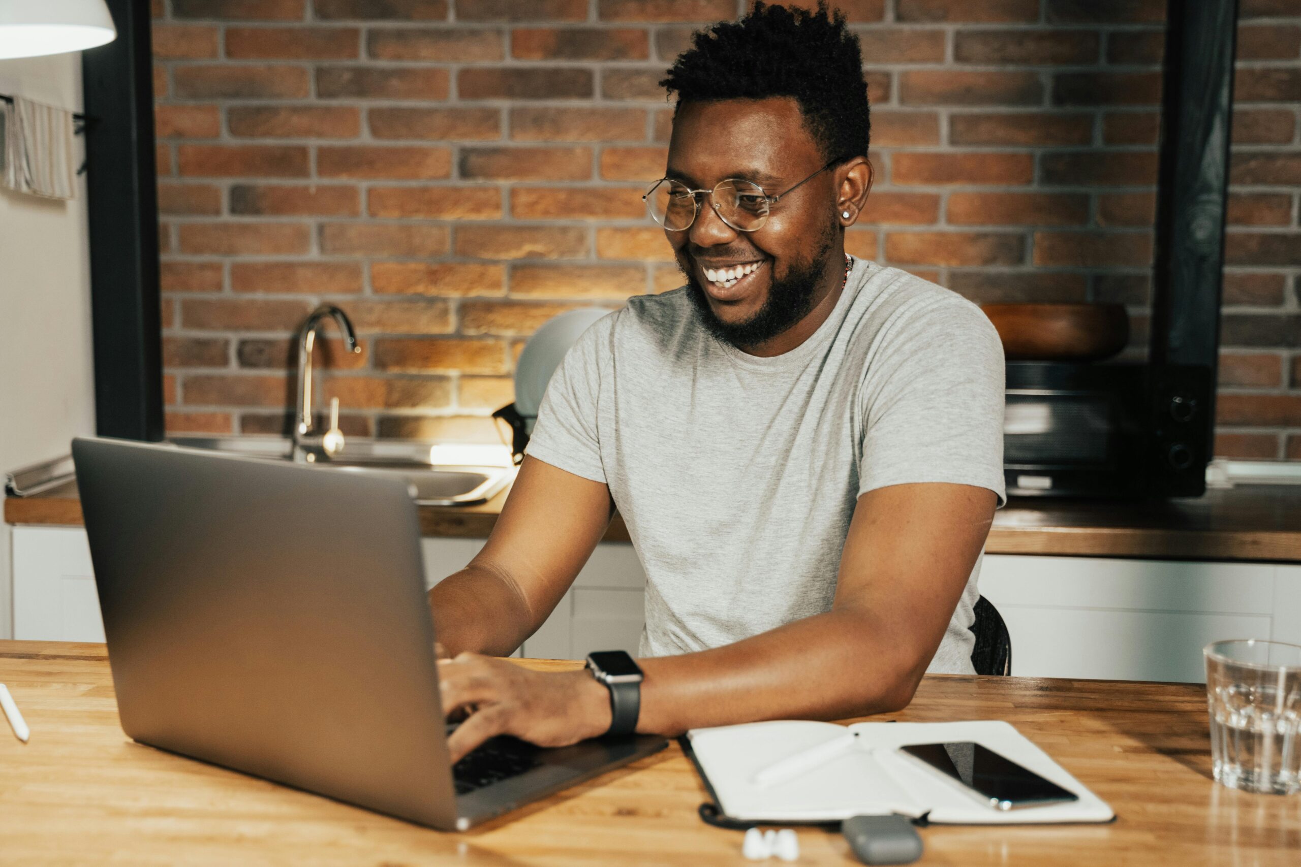 pexels-photo-5198239-5198239 African American man smiling while working remotely on laptop from home office