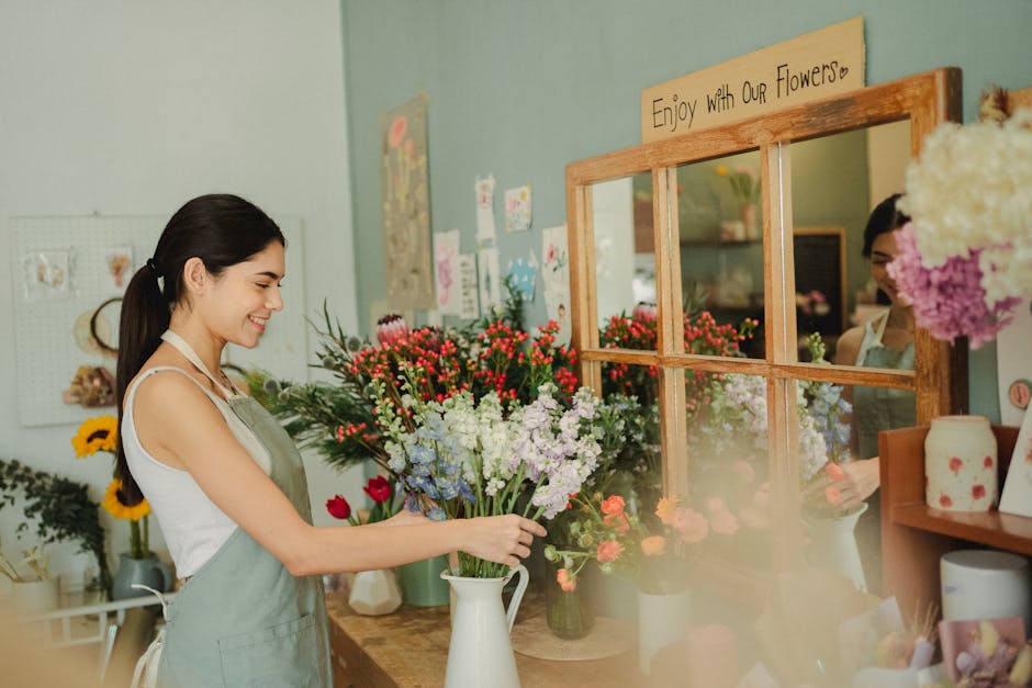 Side view of female florist arranging bouquets of fresh flowers and smiling while working in flower shop
