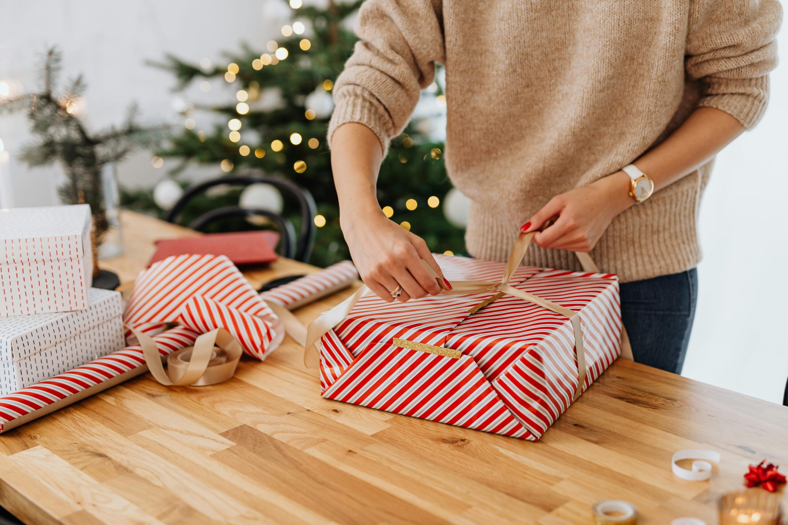 pexels-photo-5469249-5469249 A woman wrapping gifts by a Christmas tree, spreading holiday cheer.