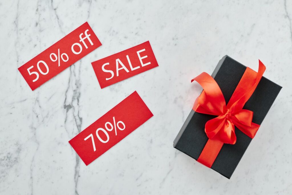 pexels-photo-5872185-5872185 Stylish black gift box with red ribbon and sale tags on marble, perfect for Black Friday promotions.