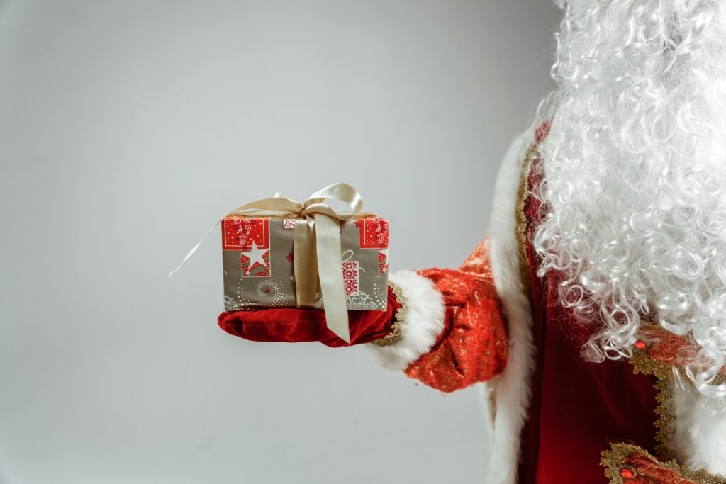 Santa Claus offering a beautifully wrapped present, perfect for Christmas themes.