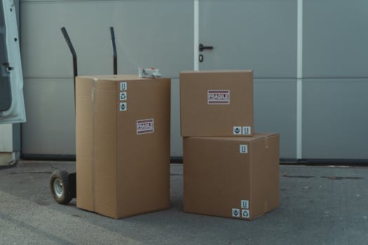 pexels-photo-6169055-6169055 Three cardboard boxes on a dolly, ready for shipping outside a warehouse.
