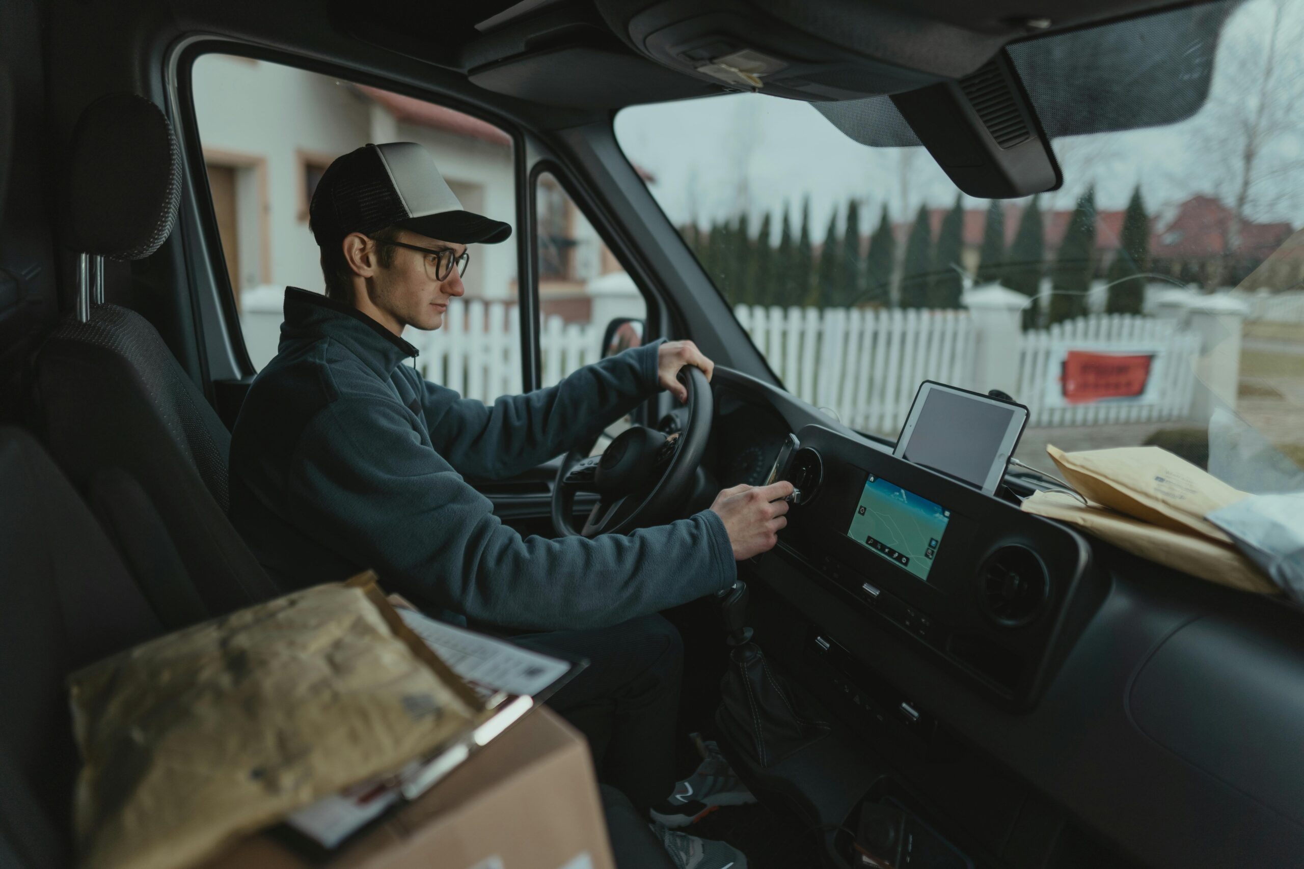 pexels-photo-6169129-6169129 Courier driving van with packages, using GPS for efficient delivery route.