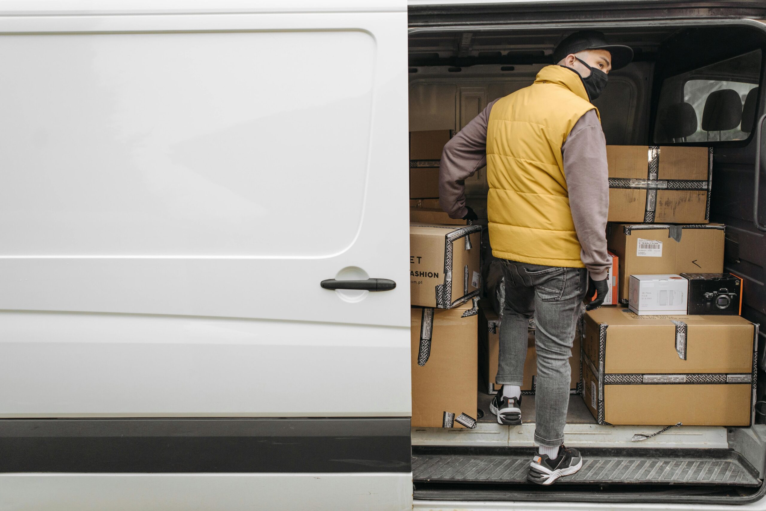 pexels-photo-6407438-6407438 A deliveryman unloading packages from a van, showcasing modern logistics.