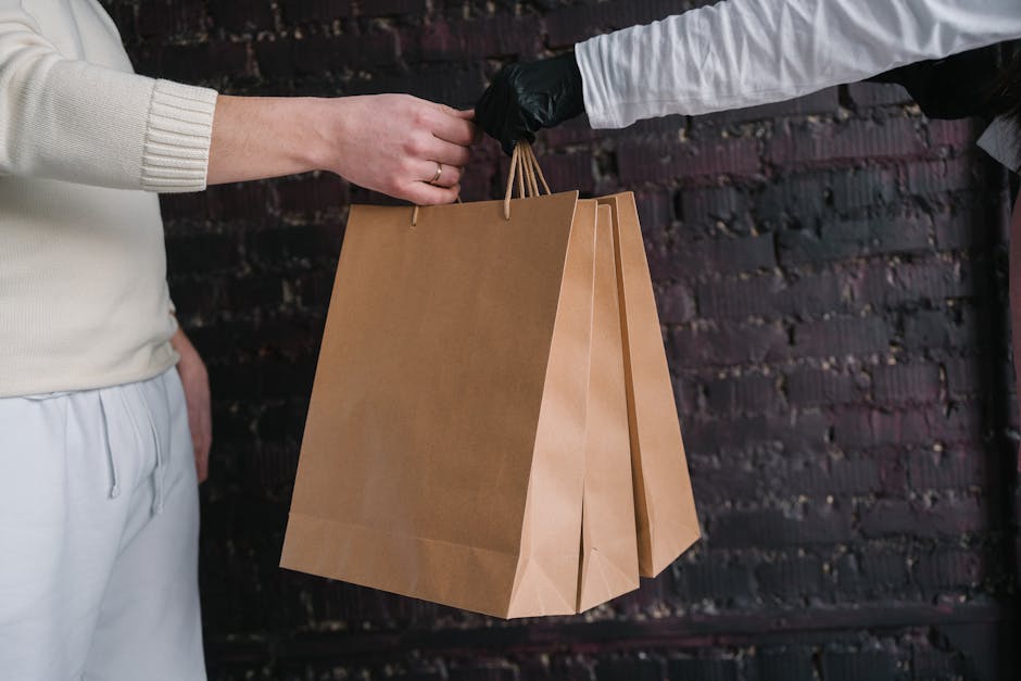 pexels-photo-6613915-6613915 Two individuals exchange paper shopping bags against a dark brick wall background.