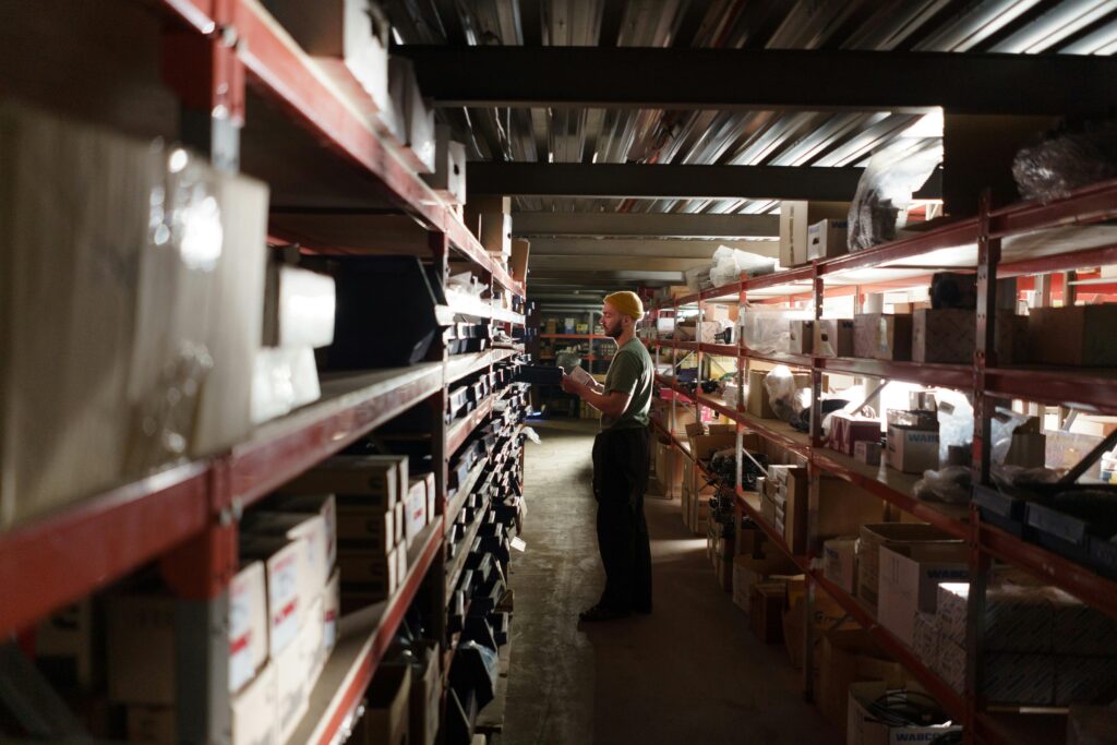 A warehouse worker sorting items on shelves in an organized storage space.
