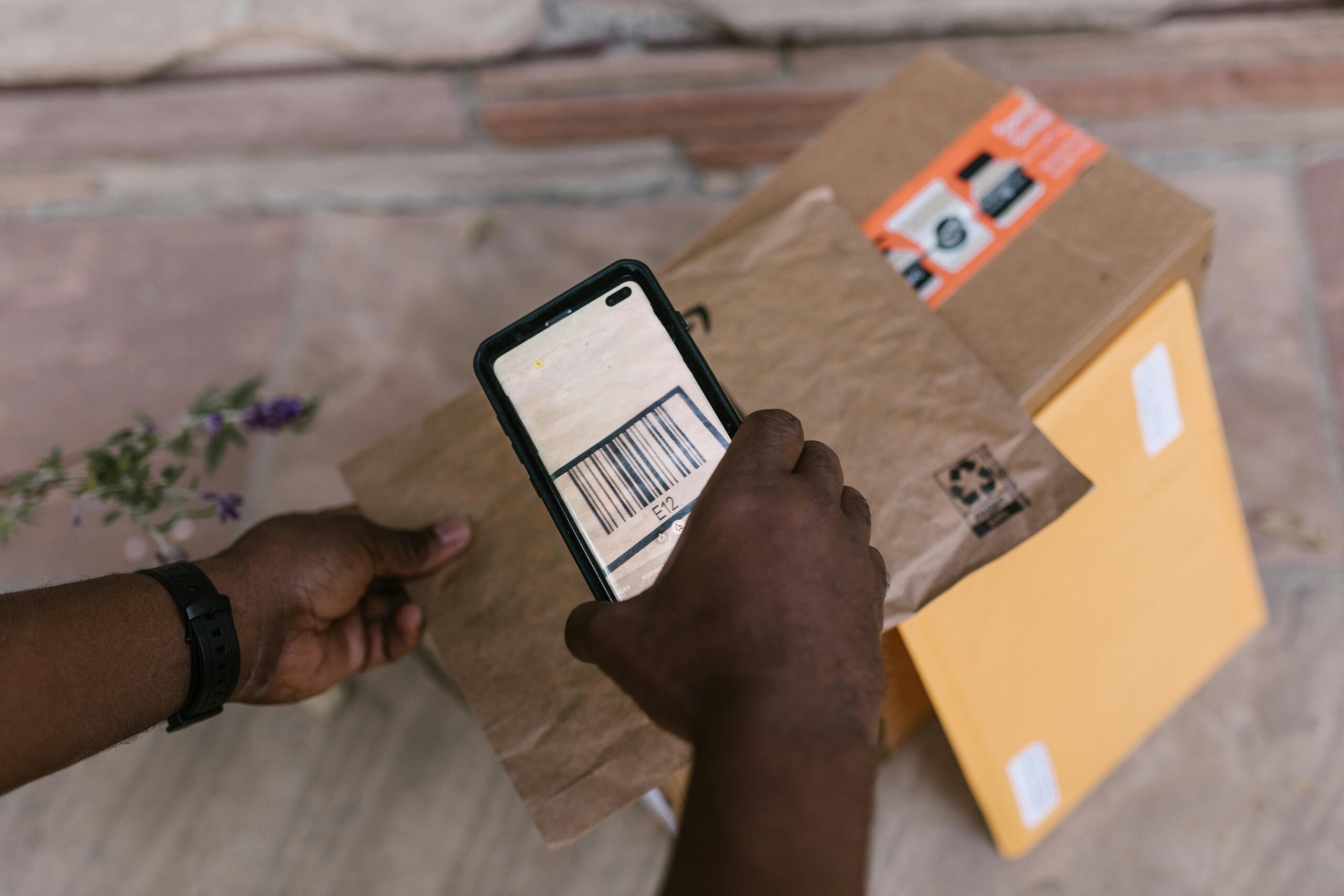 pexels-photo-7363196-7363196 A person scans package barcodes using a smartphone for delivery logistics.