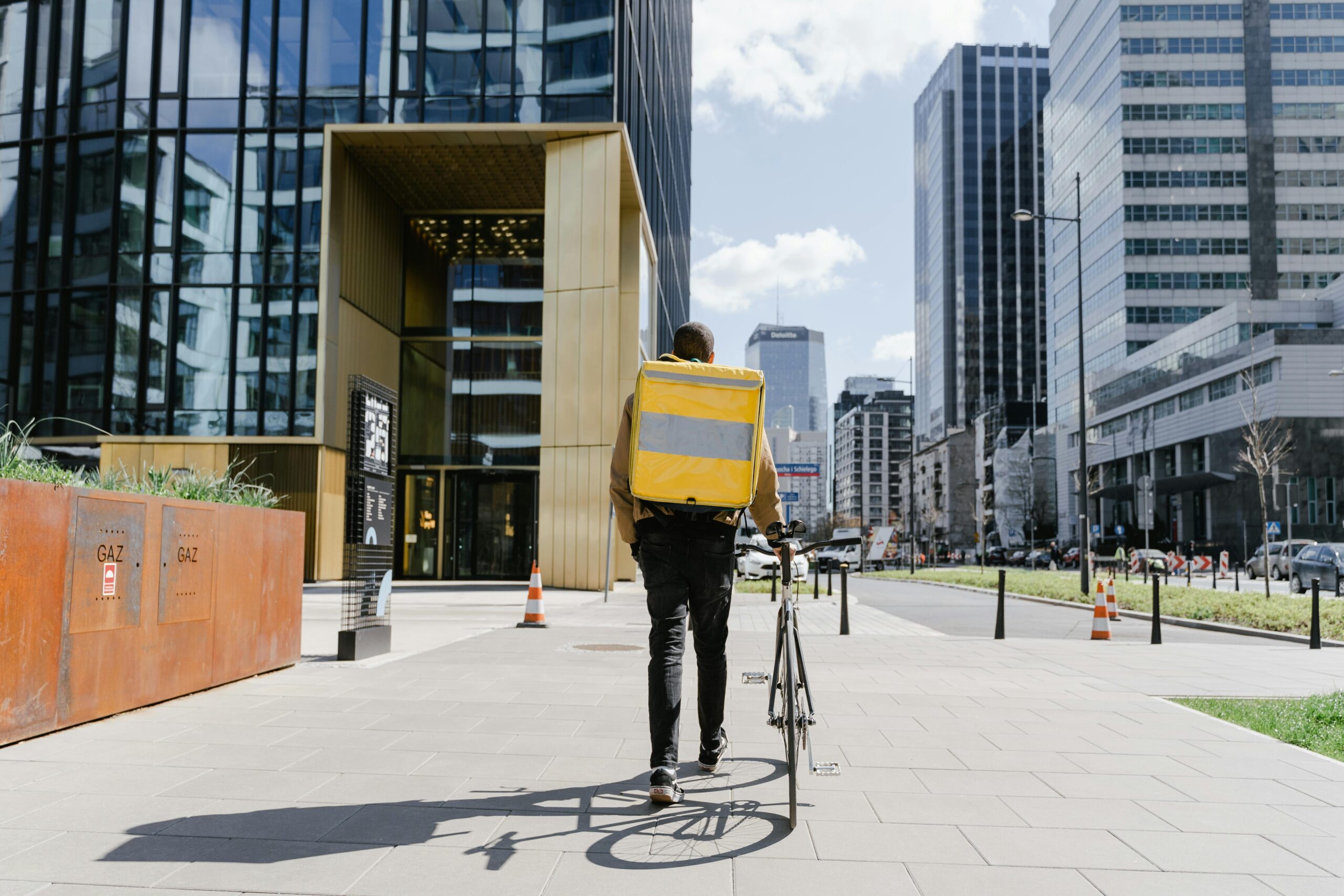 Bicycle courier with a thermal bag delivering food in a modern urban environment.