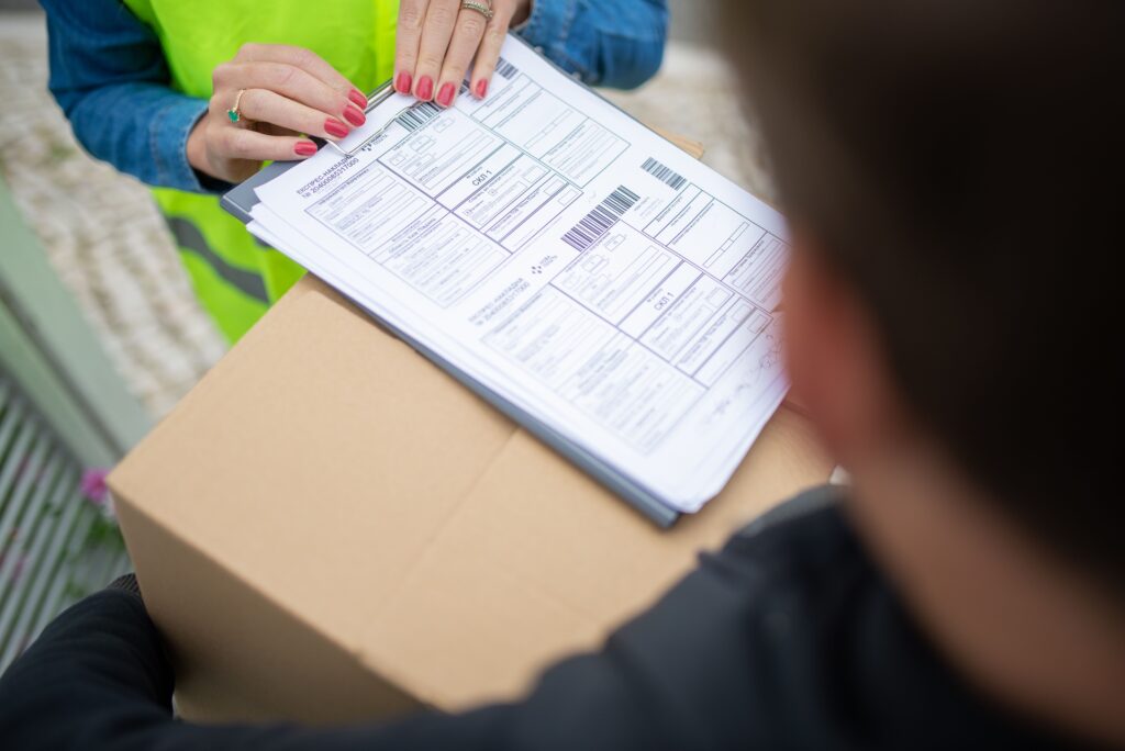 pexels-photo-7844017-7844017 Courier hands over a package for delivery with signing of receipt documents.