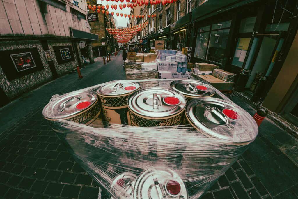 Beer kegs on Chinatown street, England, with vibrant hanging lanterns and bustling ambiance.