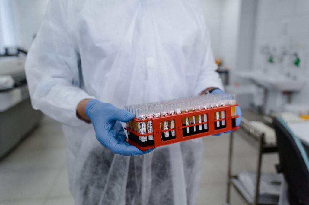 pexels-photo-9574400-9574400 Scientist in protective gear holding a rack of test tubes in a laboratory setting, highlighting research work.